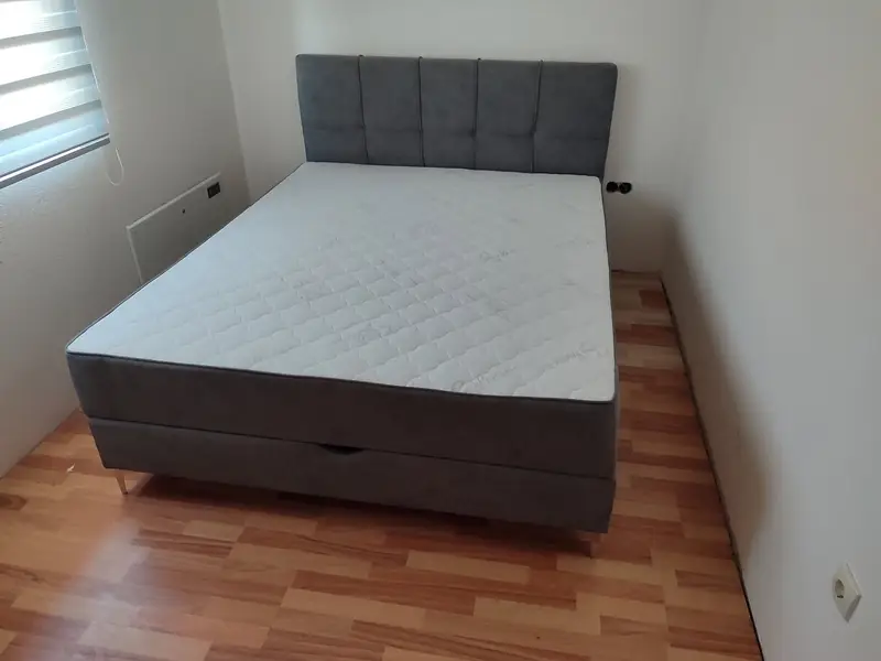 Sivi francuski ležaj s kvadratnim uzglavljem na laminatu